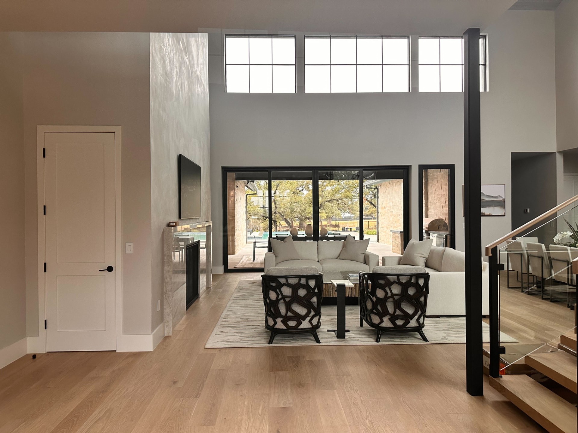 Double-height great room with a stone fireplace, integrated television, and glass sliders to the pool
