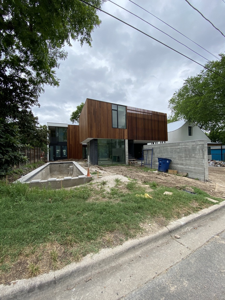 Modern Austin home under construction with an unfinished pool basin and open grounds