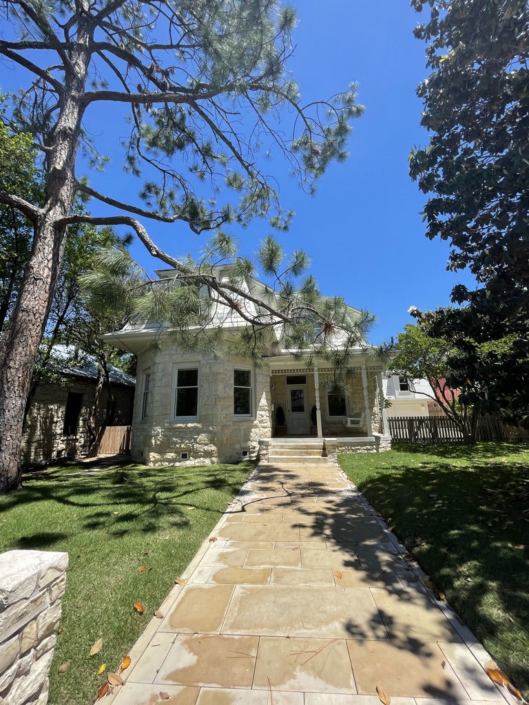 Stone-clad Austin home exterior with a stone walkway and mature pine