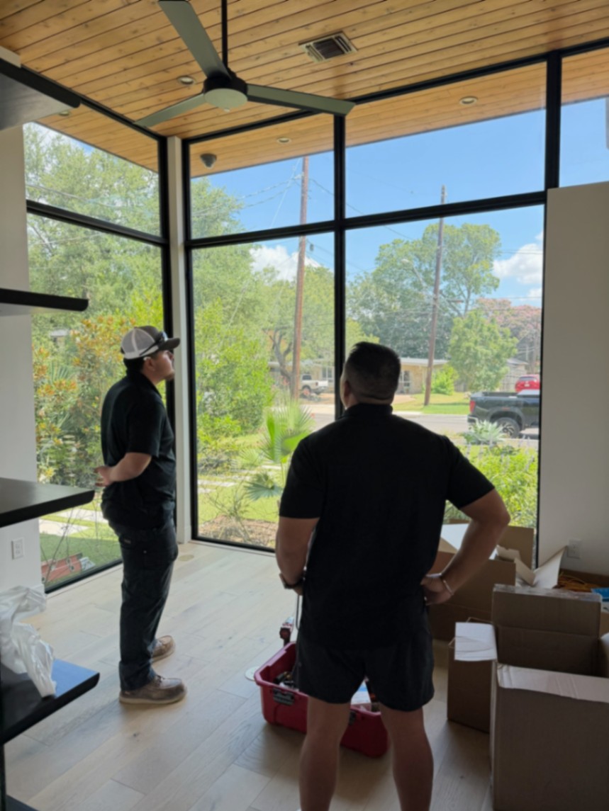 ATX Smart Homes team walking through a glass-walled room during a site survey, reviewing equipment locations