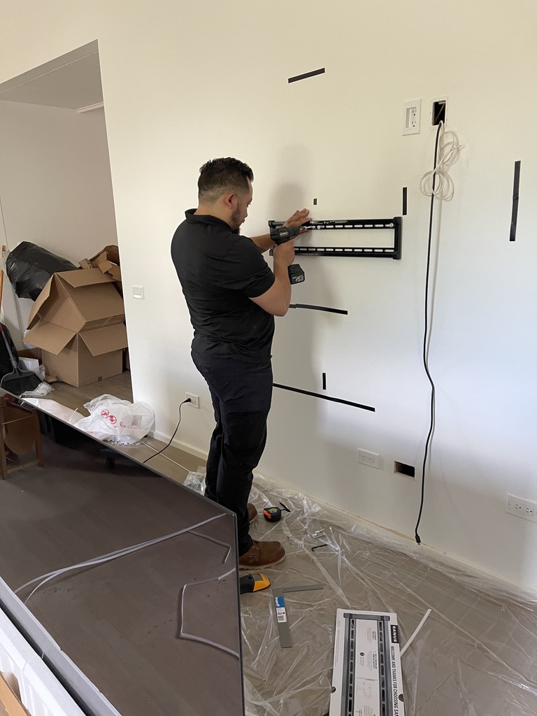 Technician mounting a television bracket in a residential room