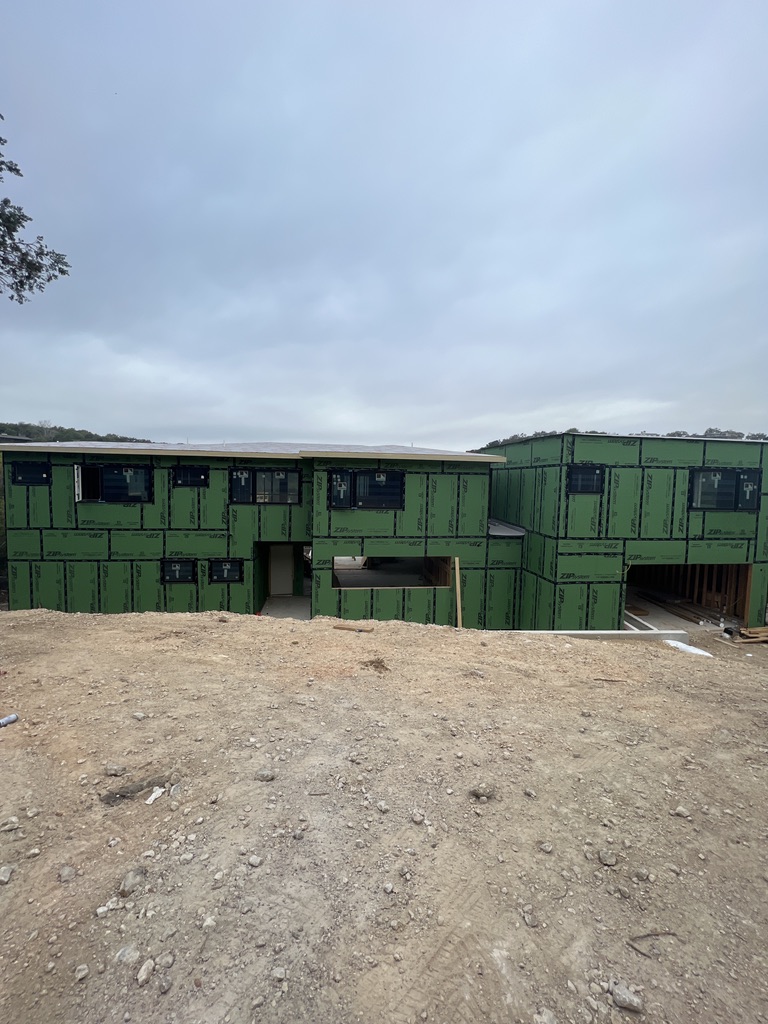 Modern residence under construction with sheathing and installed windows on an Austin lot