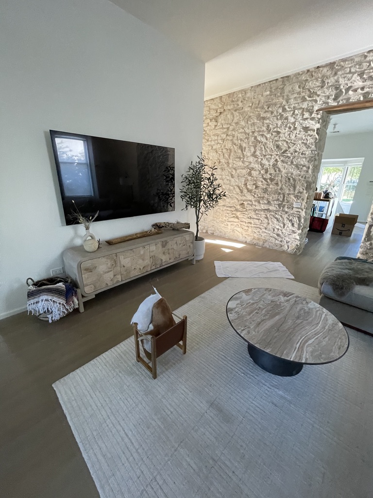 Finished living room with a wall-mounted television and stone feature wall