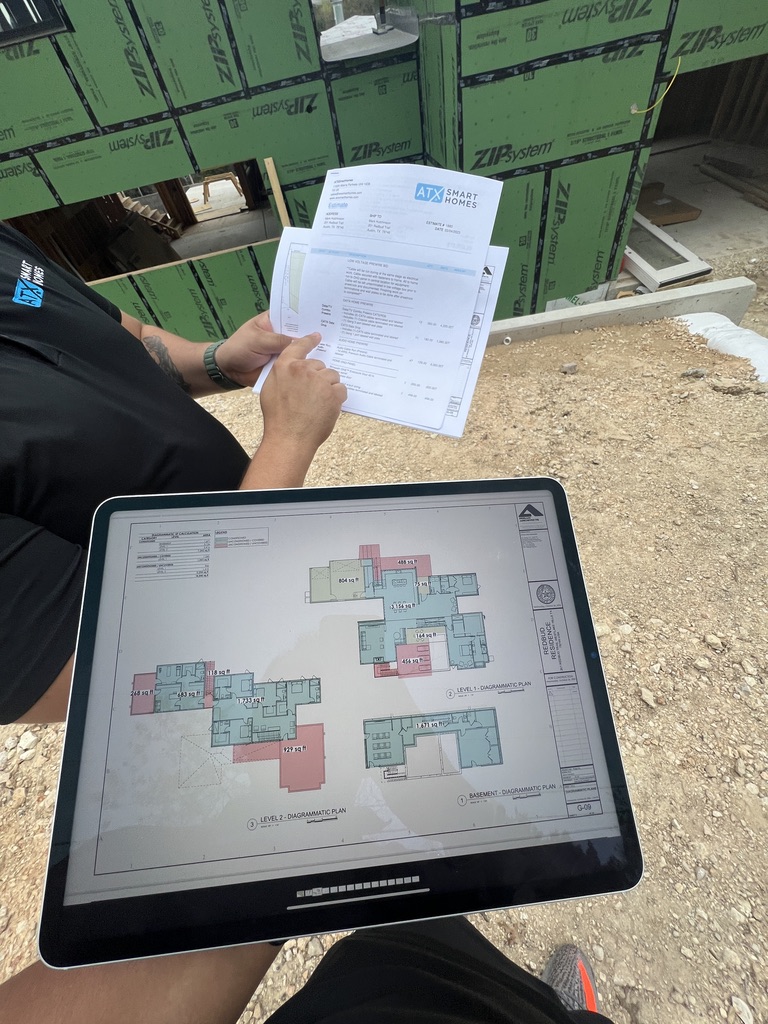 ATX Smart Homes team reviewing floor plans on a tablet and a printed estimate on site