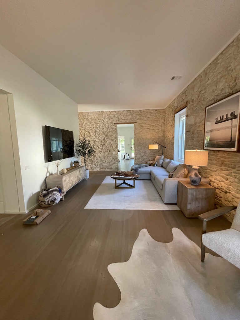 Finished living room with a wall-mounted television, stone walls, and a low media cabinet
